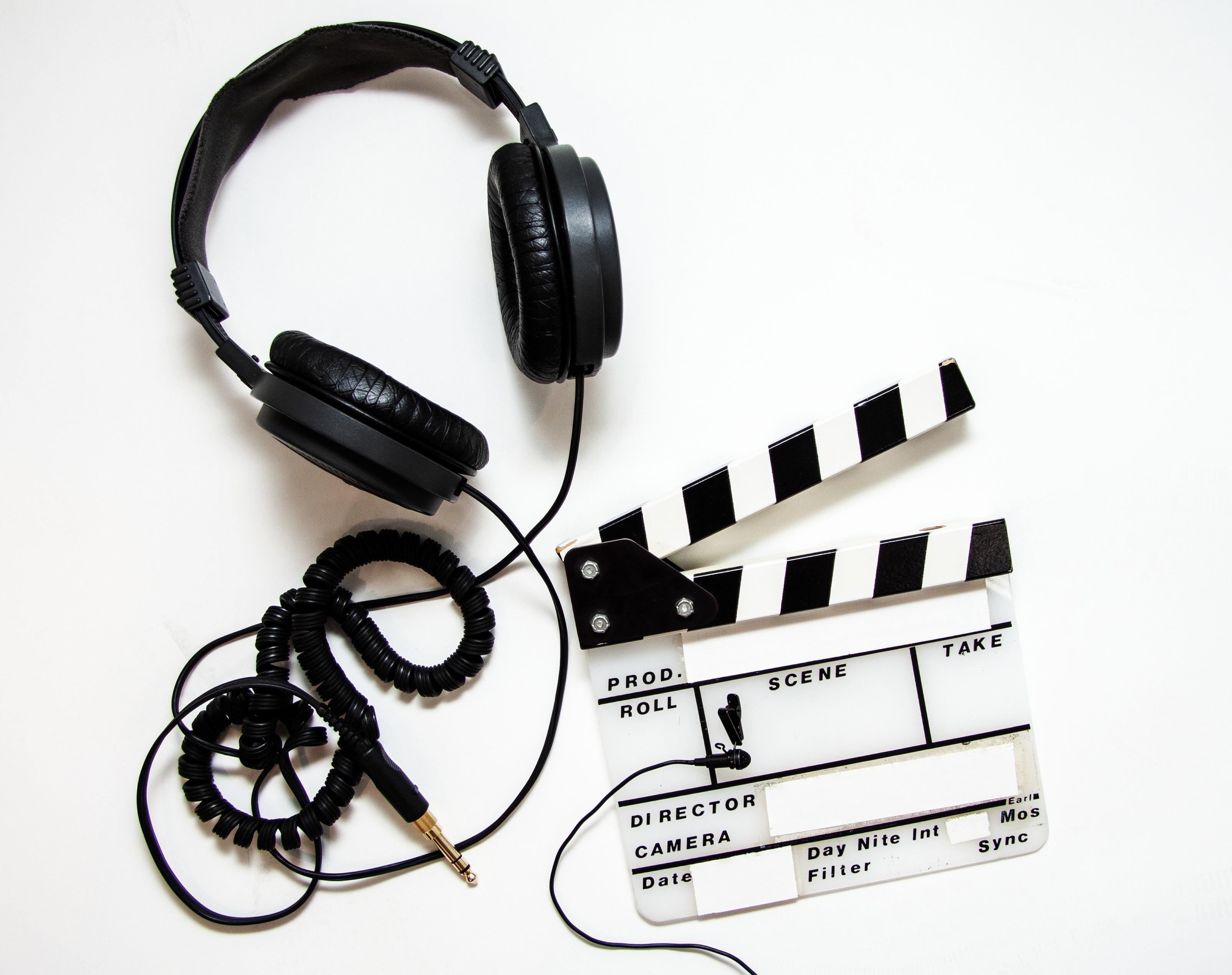 Hörlurar och en klappklapp med texten ”'PROD ROLL SCENE TAKE'”.
