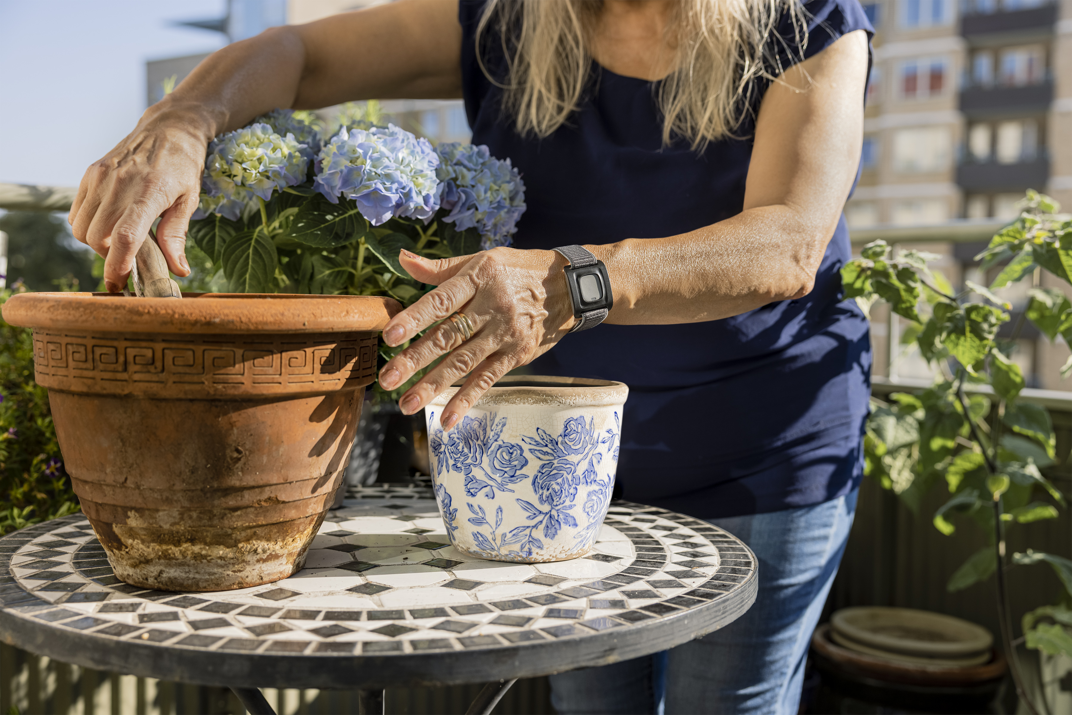Person planterar blommor. På armen har hon en larmknapp.