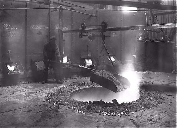 svartvitt foto på en man som arbetar i ett järnbruk