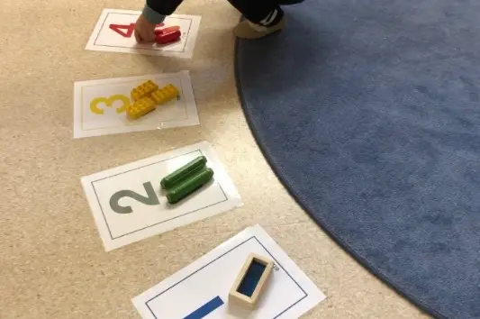 Foto på siffror som ligger på golvet, vid varje siffra finns lika många saker som siffran visar.