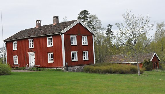 ett rött äldre hus med vita knutar.