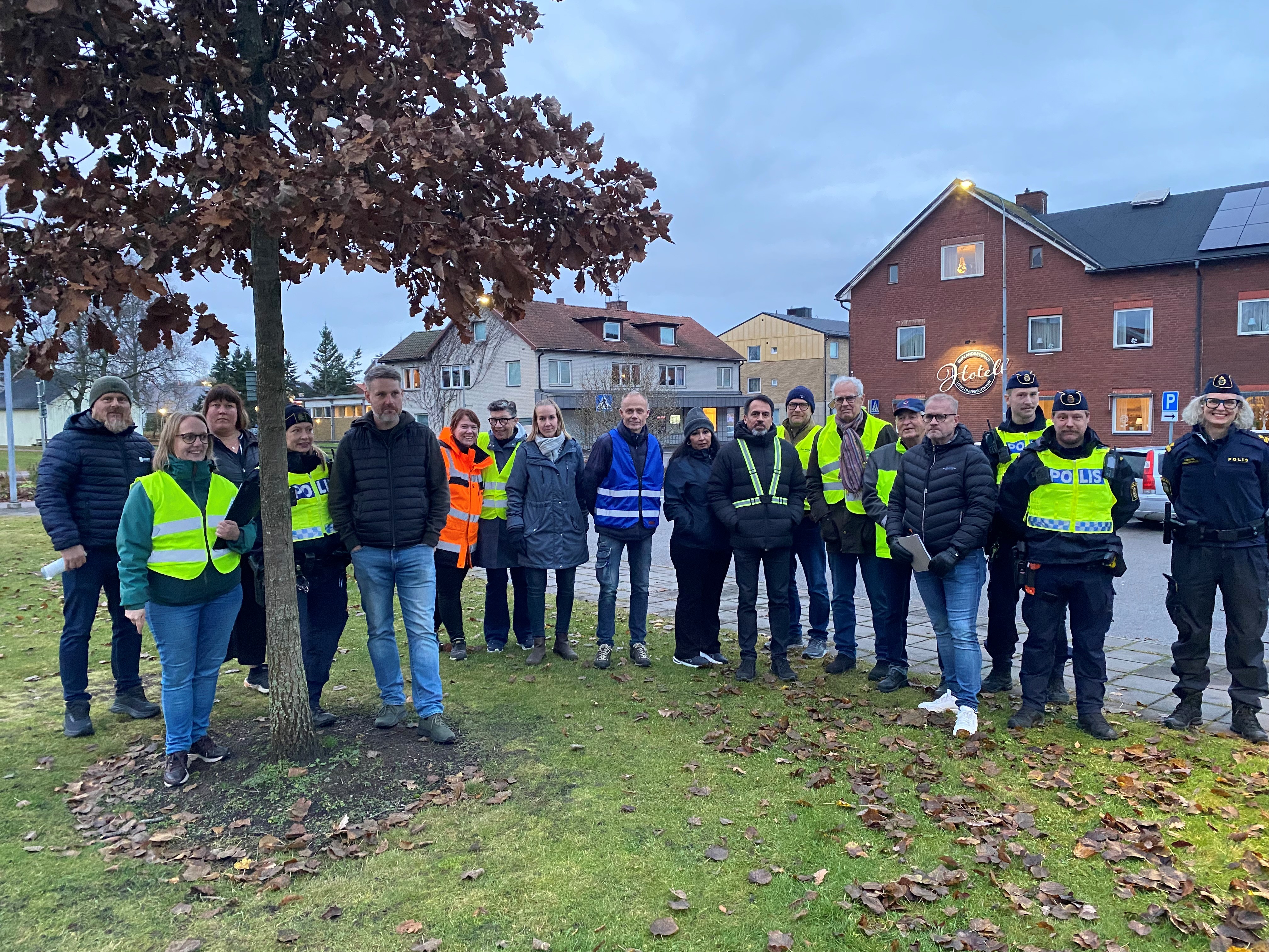 Ett tjugotal personer står uppradade utomhus. Några av dem bär reflexvästar och några bär polisuniform.