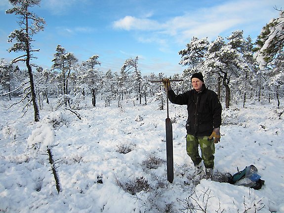 en man stående i en snötäckt mosse med en stor skruv.