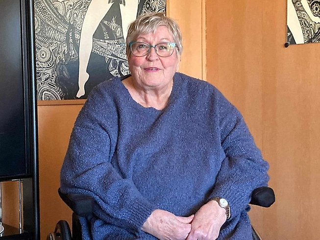 Glad äldre dam i rullstol.