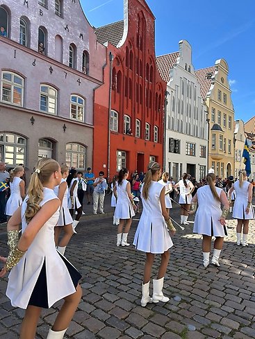 Byggnader i Hansastil och en grupp drill-flickor i förgrunden.