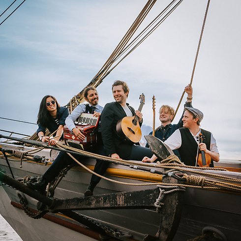 5 personer som sitter i en segelbåt och ser glada ut