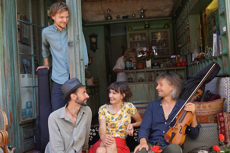 4 glada personer som håller i instrument och tittar på varandra