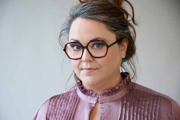 en allvarlig kvinna med glasögon och håret uppsatt