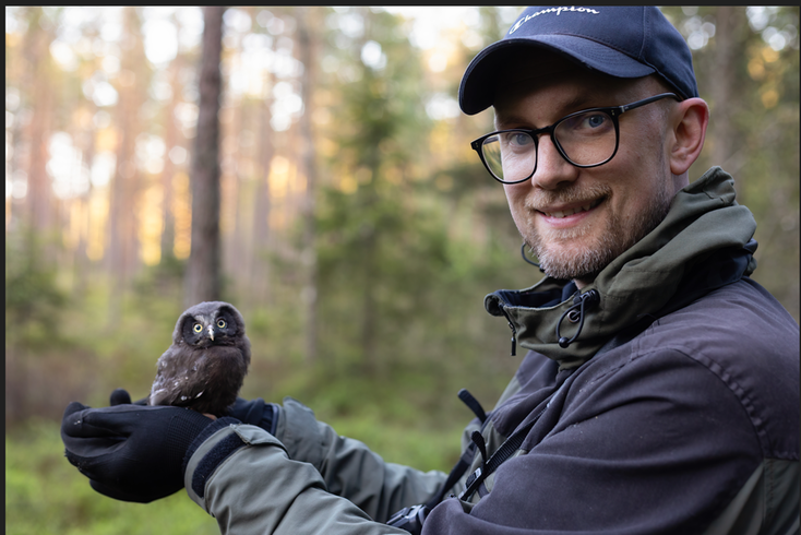 en man som håller i en liten uggla i skogen