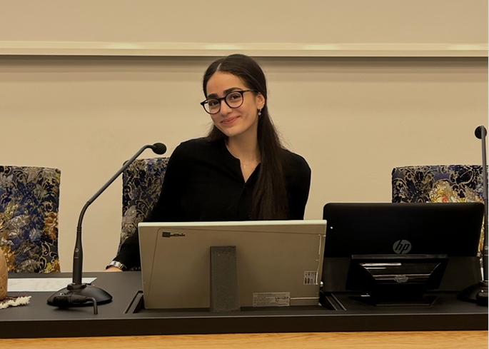 Foto på en tjej med glasögon som sitter vid ett stort skrivbord.