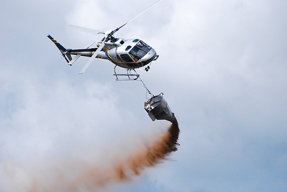 helikopter sprider kalk över en sjö.