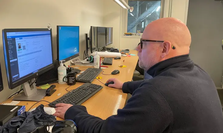 En man som sitter vid ett skrivbord med flera datorskärmar.