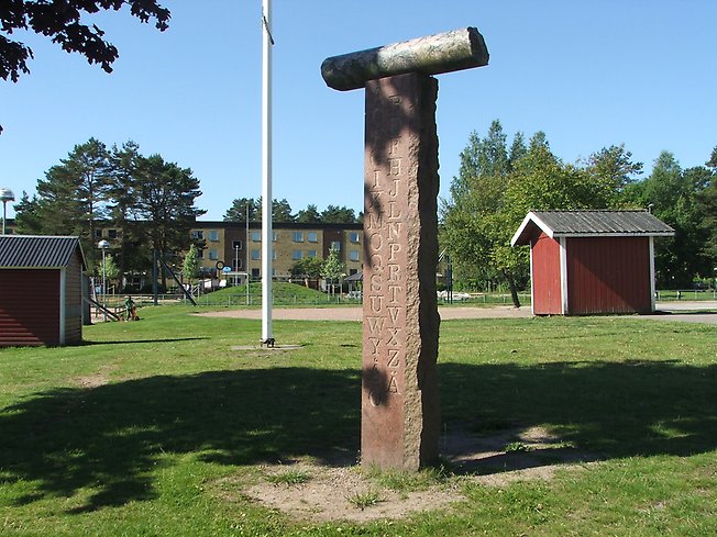 staty av en budkavel på en lång och hög sten med namn i ingraverat