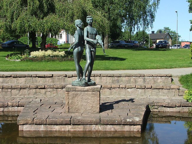 skulptur av ett par i en damm med en fiol i en park