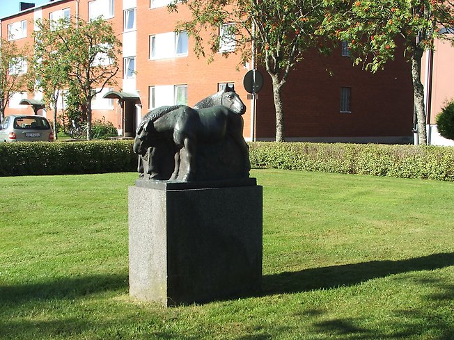 skulptur av hästar i sten som står brevid varandra i en grön park