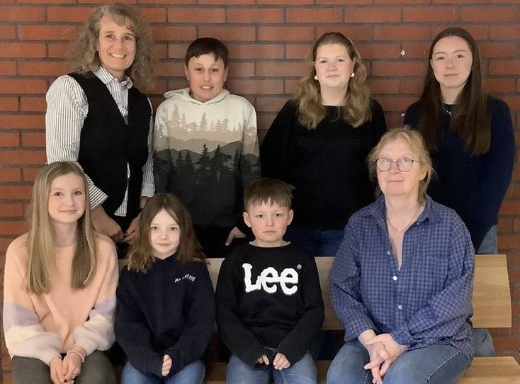 En grupp elever och pedagoger framför en tegelvägg.