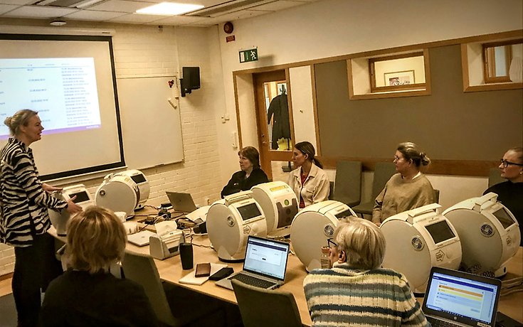 Medarbetare inom kommunen sitter i ett konferensrum och lär sig hur läkemedelsgivaren fungerar. på konferensbordet står ett 10-tal läkemedelsgivare.