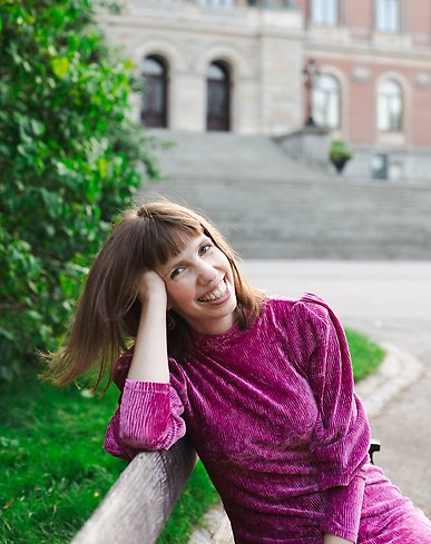 en glad kvinna som sitter på en parkbänk i en glittrig kläning