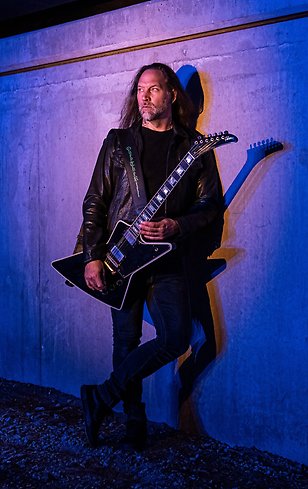 en man med en gitarr ståendes mot en vägg