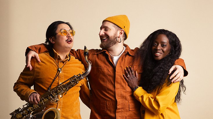 en man som håller om en annan man med saxofon och en glad kvinna