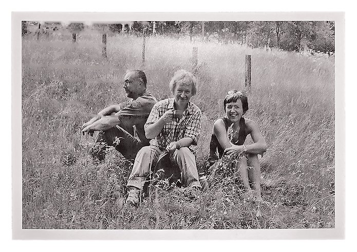 ett äldre foto på tre personer som sitter på en äng