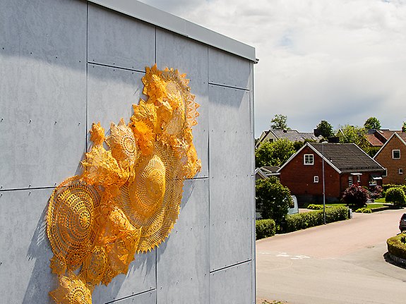 ett kostverk i form av virkade dukar som sitter uppspänt på sporthallen i Smålandsstenar