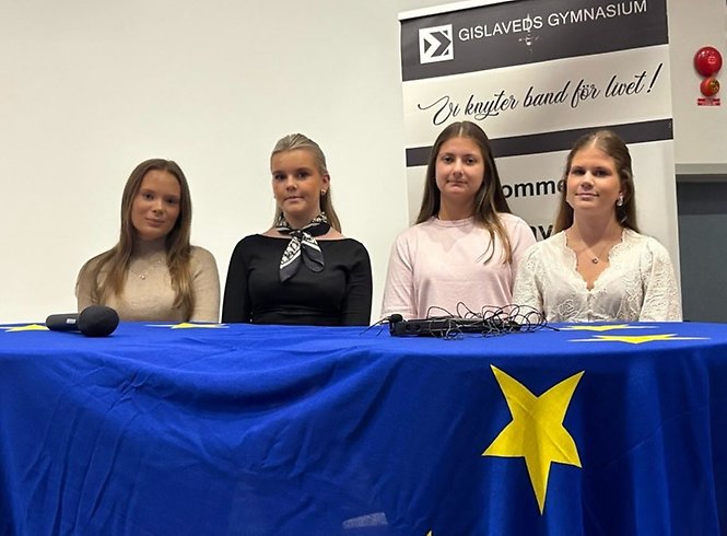 Fyra personer sitter bakom ett bord täckt med en blå duk.