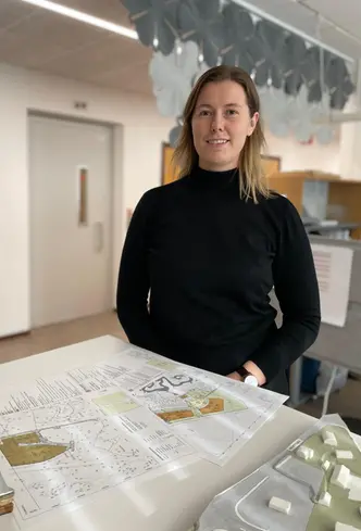 Julia står framför ett bord där det ligger plankartor