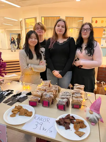 Foto på fyra elever som säljer kakor.
