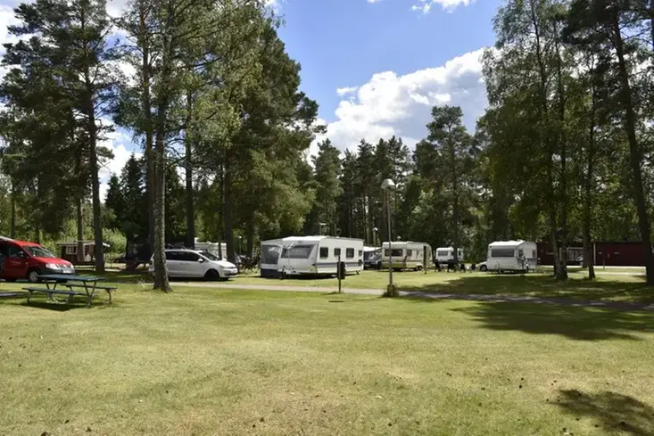 Bild på campingen under sommartid, gräsyta, träd och husvagnar