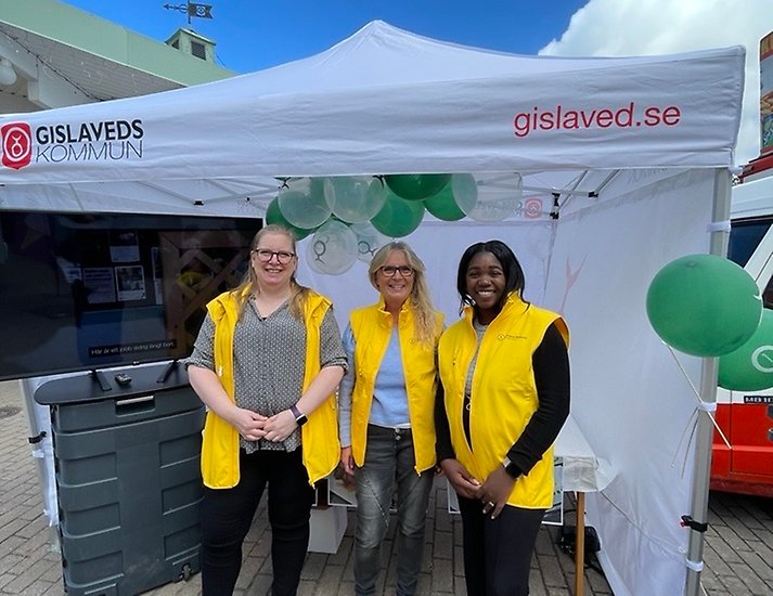 Ett utställningstält där tre medarbetare i citrongula västar står.