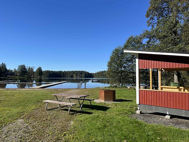 Badplats vid en sjö med grillstuga