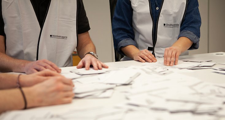 Tre röstmottagare som räknar röstkort.