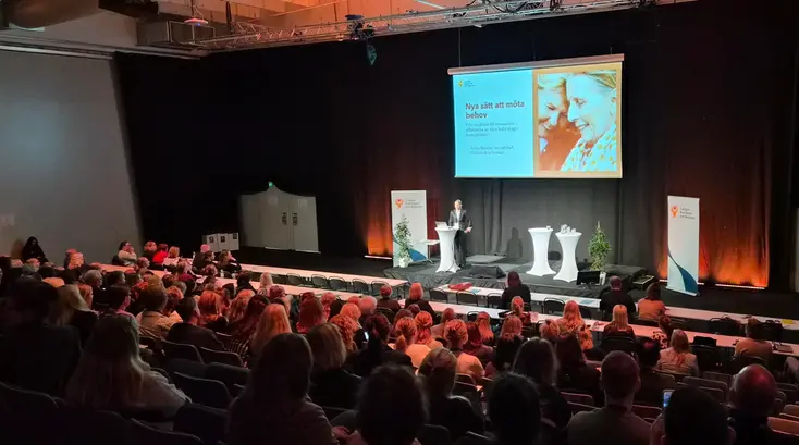 Översiktsbild frå bakre delen av lokalen. Alma Maslan står på scen. Publiken lyssnar.