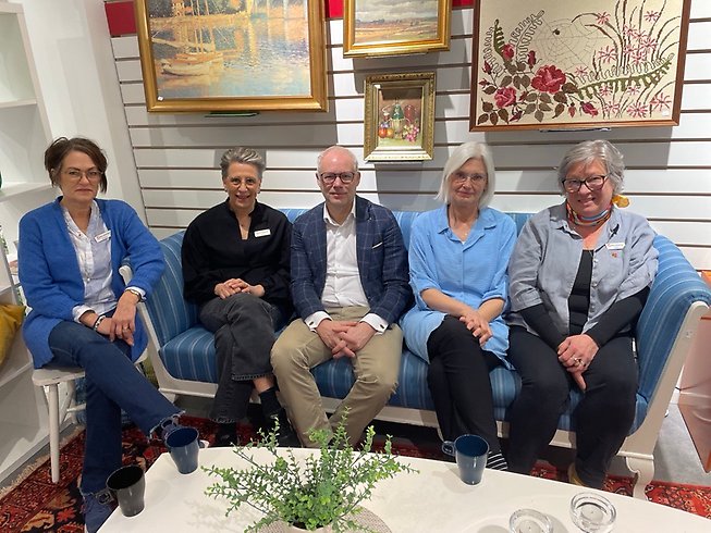 Fem personer sitter tillsammans vid en soffa.