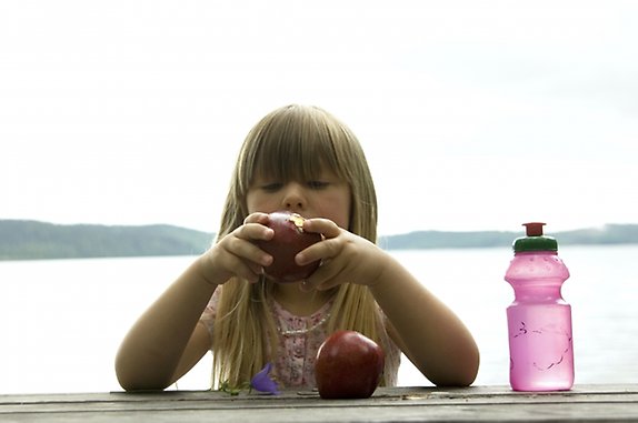 Bilden visar en flicka som äter ett äpple