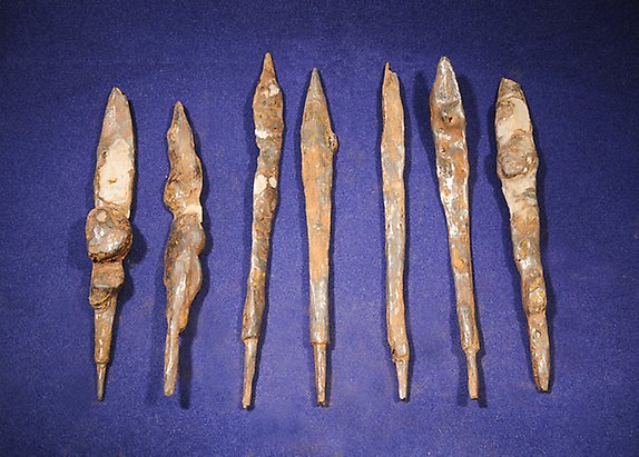Dessa sju pilspetsar hittades tätt tillsammans i en av gravarna. Pilarna har ett lancettformat blad med kort hals och markerad tånge. Detta är en av de vanligaste piltyperna under vikingatiden. 