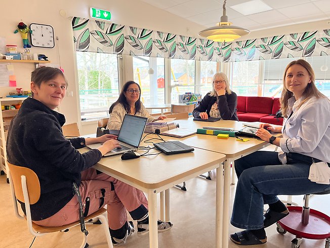 Foto på personal som sitter runt ett bord och pratar.