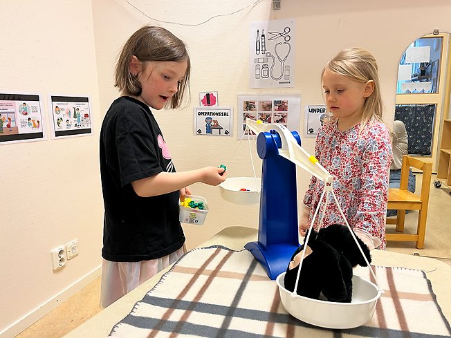 Foto på två barn som väger en hund.