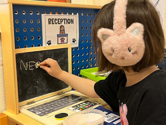 Foto på ett barn som skriver på en griffeltavla.