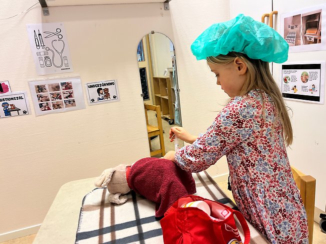 Foto på barn i kirurgmössa som undersöker en hund.