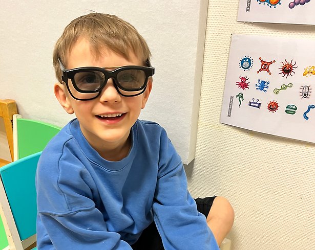 Foto på ett barn med flera glasögon på sig.